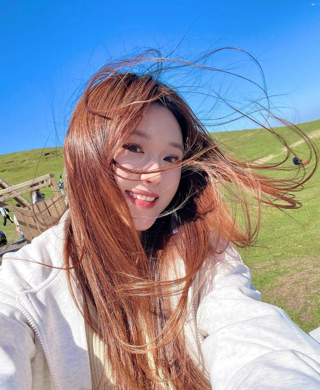 Smiling in a grassy field as the wind lifts long hair