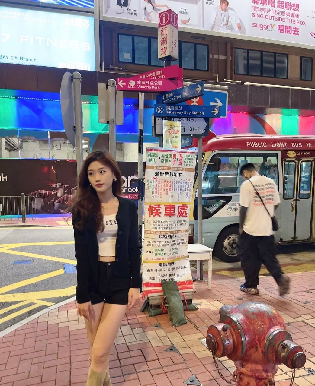 Full-length street-style photo beside a bus stop at night