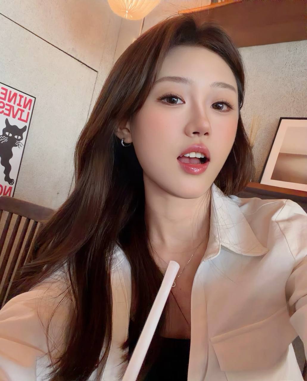Close-up selfie in a white shirt at a cafe