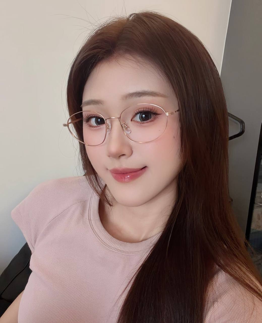 Close-up selfie in a pale pink top and thin-framed glasses